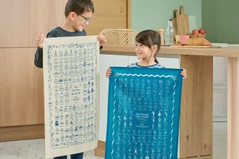 Deux enfants présentent des torchons personnalisés avec dessins d’école, objets souvenirs à prix dégressif